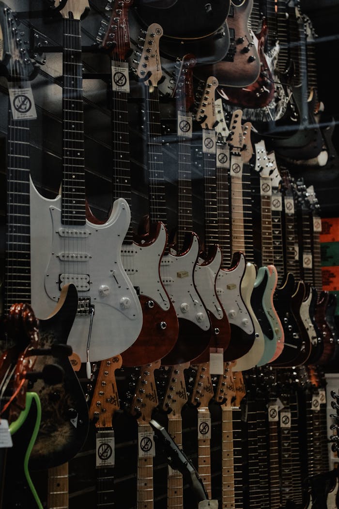 A vertical shot of assorted electric guitars hanging on a wall display in a music store.