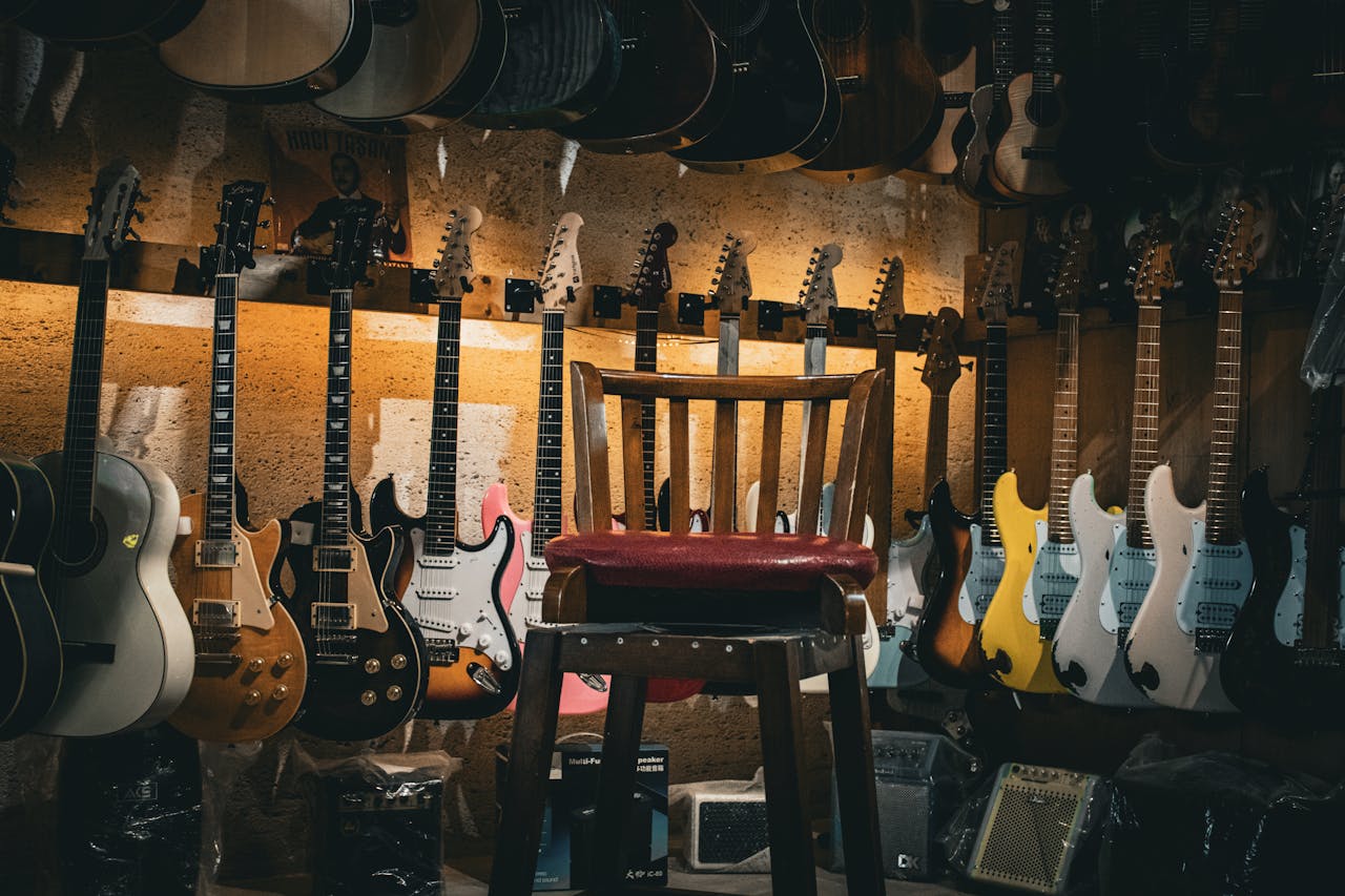 A cozy music store with a variety of guitars on display and a single chair in the center.